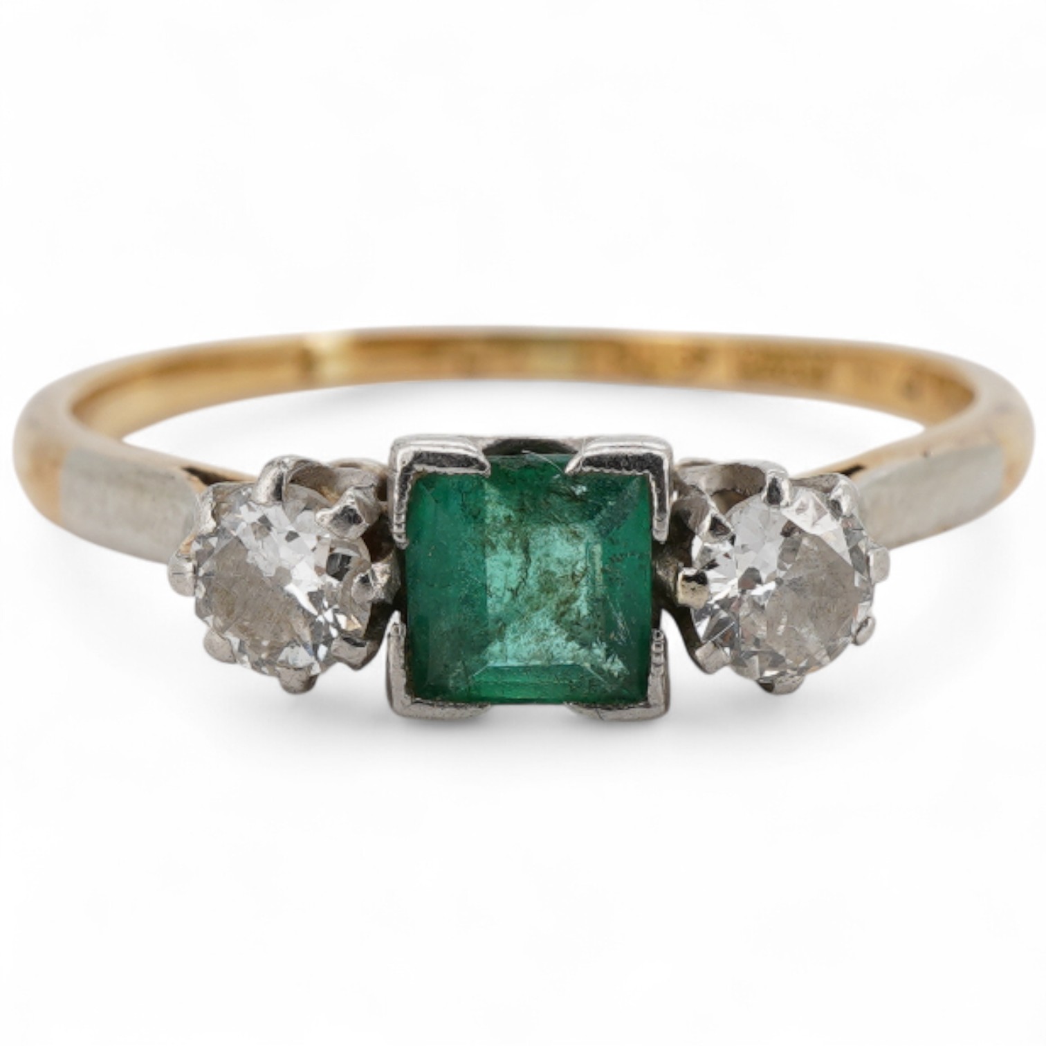 A yellow metal, single stone emerald and two stone diamond set ring, the emerald measuring approximately 4.3mm, the diamonds approximately 0.15ct each, the shank stamped with maker's mark HS and 'Plat', size P/Q.